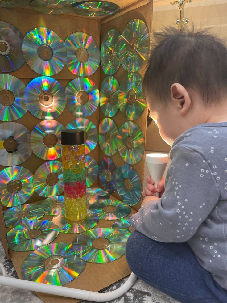 a small child sitting on the floor looking at cd's in a storage unit