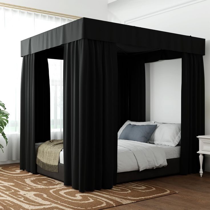 a black canopy bed with curtains on the sides and pillows on the floor in front of it