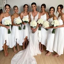 a group of women in white dresses standing next to each other holding bouquets and flowers