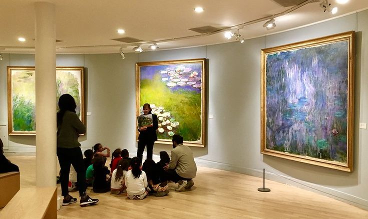 a group of people looking at paintings in a museum