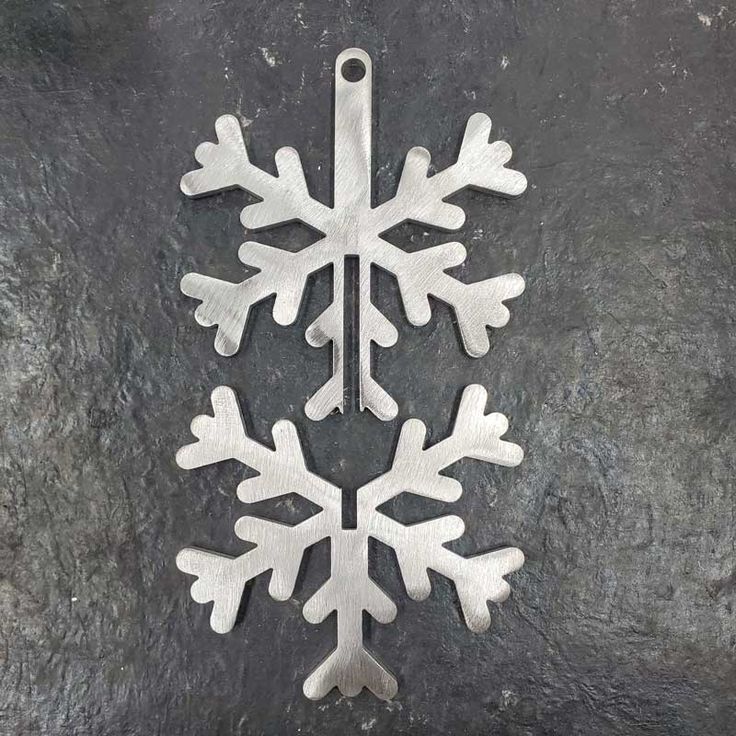 a snowflake ornament is shown on a black stone surface and it appears to be made out of metal