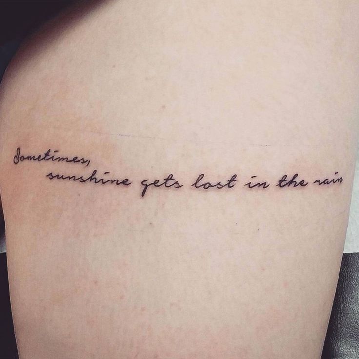 someone got this in the rain tattoo on her left thigh and it says sometimes sunshine get lost in the rain