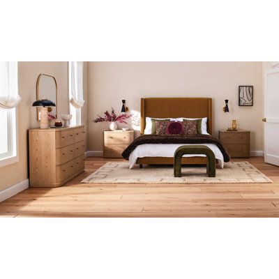 a bed room with a neatly made bed and dressers