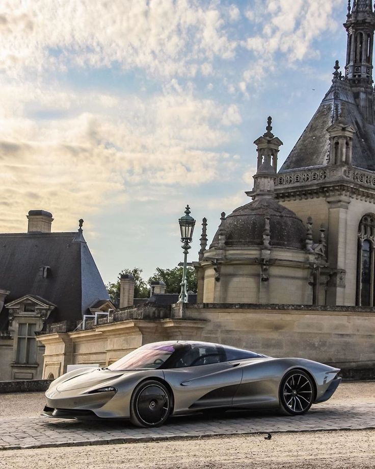 a silver sports car parked in front of a large building with a steeple on top