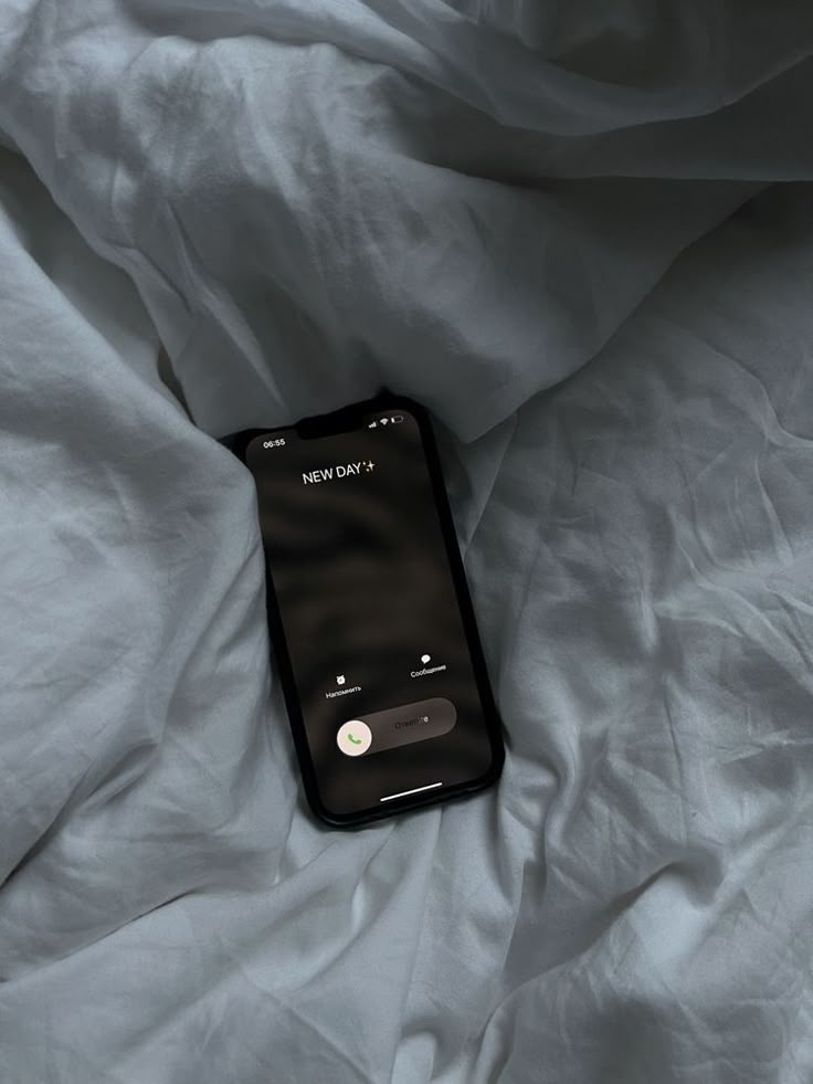 an iphone laying on top of a bed covered in white sheets