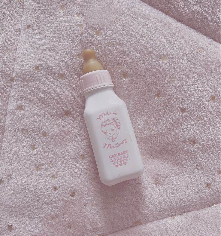 a baby bottle sitting on top of a pink blanket