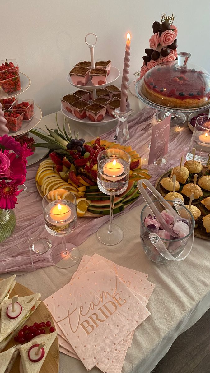 a table topped with cakes and desserts covered in frosting next to lit candles