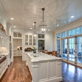 a large kitchen with wooden floors and white cabinets on the walls, along with glass doors that lead to an outdoor deck