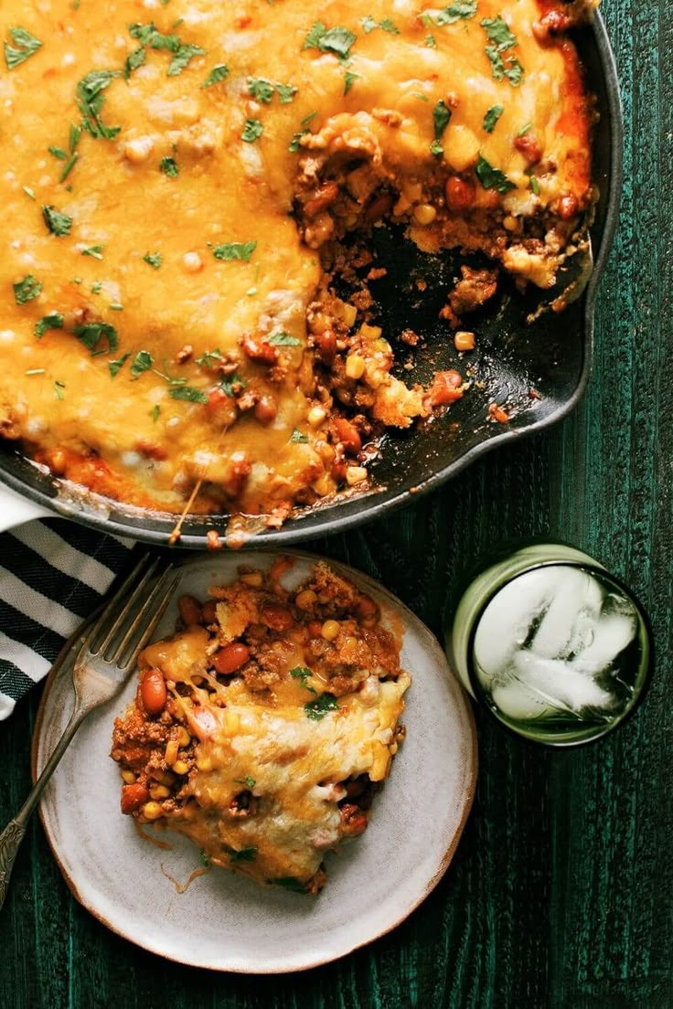 a casserole dish with meat and vegetables in it next to a glass of milk