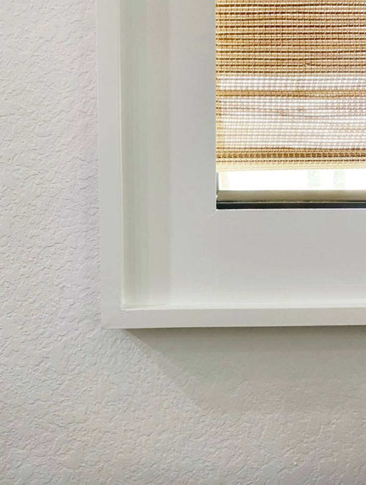 a white frame with a brown and tan striped window blind hanging on it's side