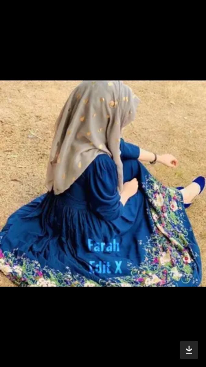 a woman sitting on the ground wearing a blue dress and head scarf, with her legs crossed