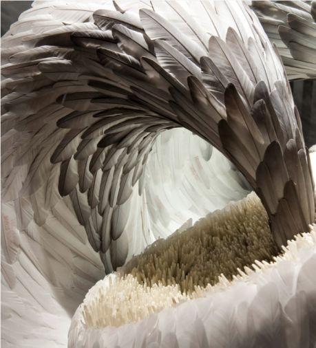 an artistic sculpture made out of white and brown paper with large feathers on it's wings