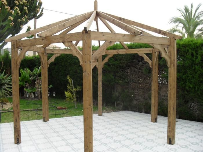 a wooden gazebo sitting on top of a white tile floor next to a tree