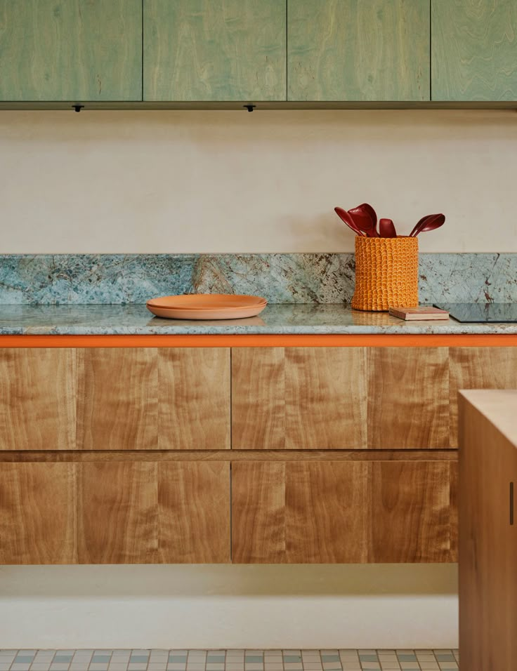 a kitchen counter with wooden cabinets and bowls on the top, along with a vase filled with flowers