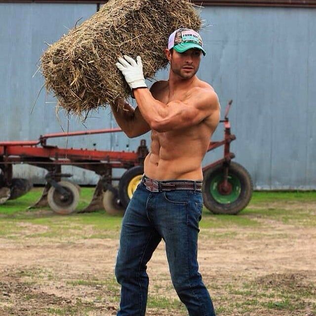 a shirtless man carrying hay in his hands