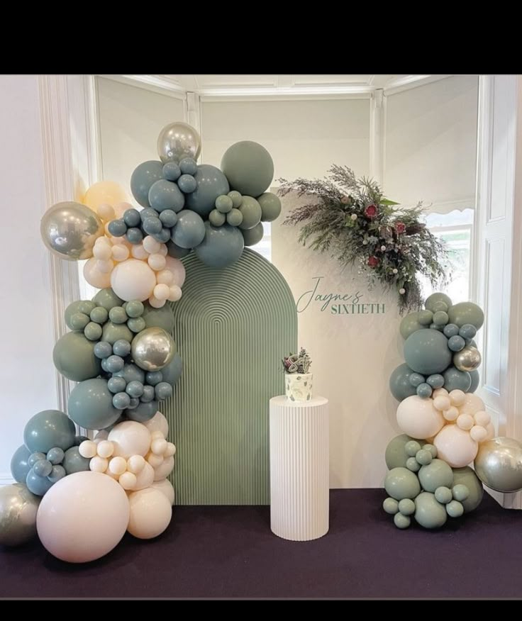 an arch made out of balloons and greenery is displayed in front of a doorway