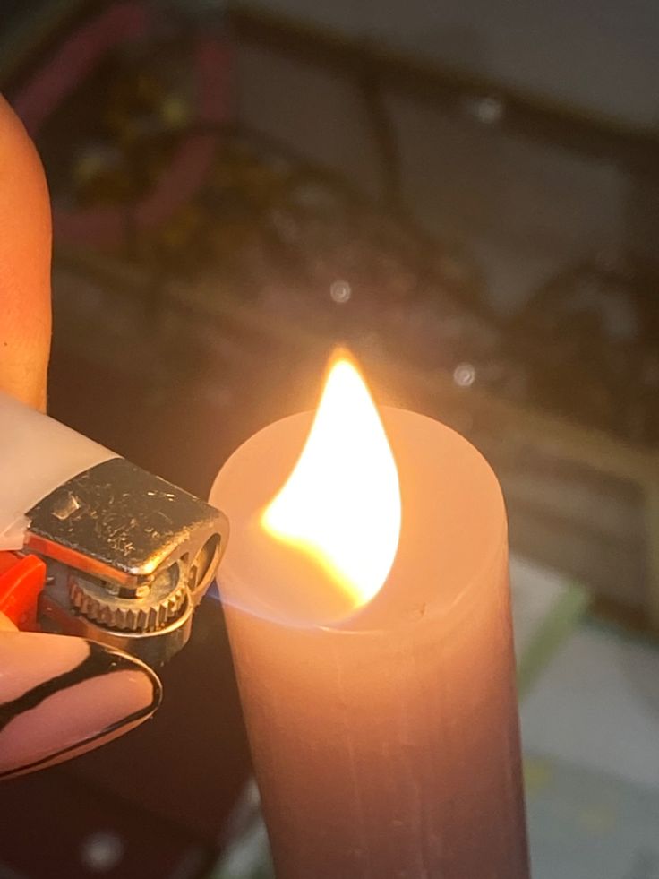 a person holding a lighter in their hand next to a candle with a lighter on it