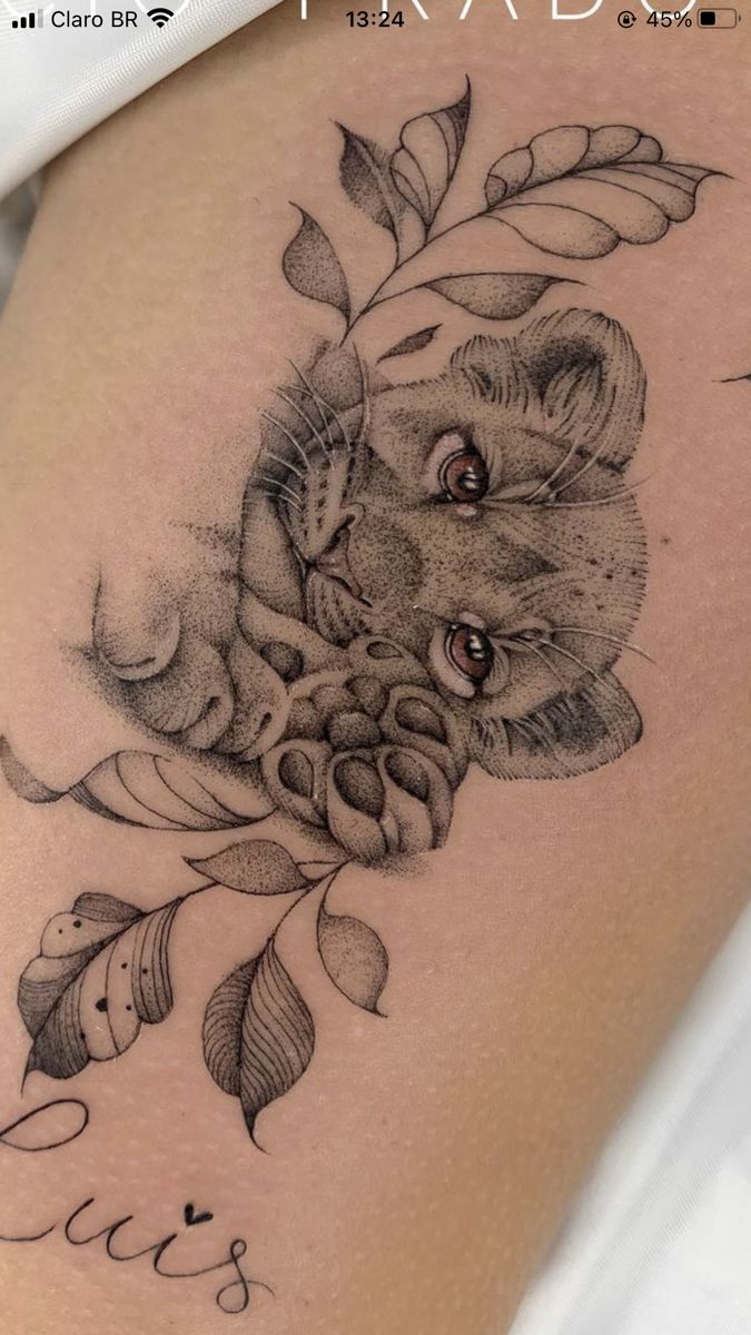 a tattoo with a cat on it's thigh and some leaves around it,