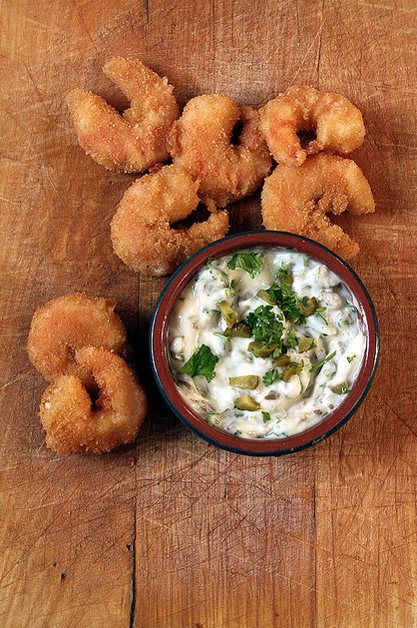 some fried food is in a bowl on a wooden table with dipping sauce and broccoli