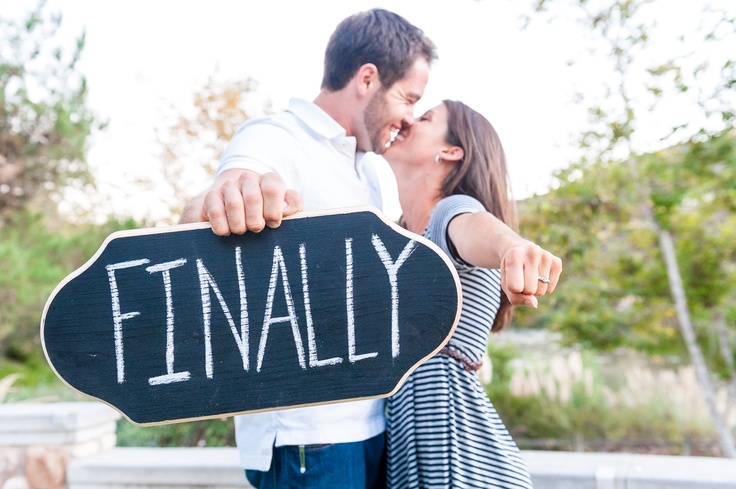 a man and woman are kissing while holding a sign that says'finally'in front of them