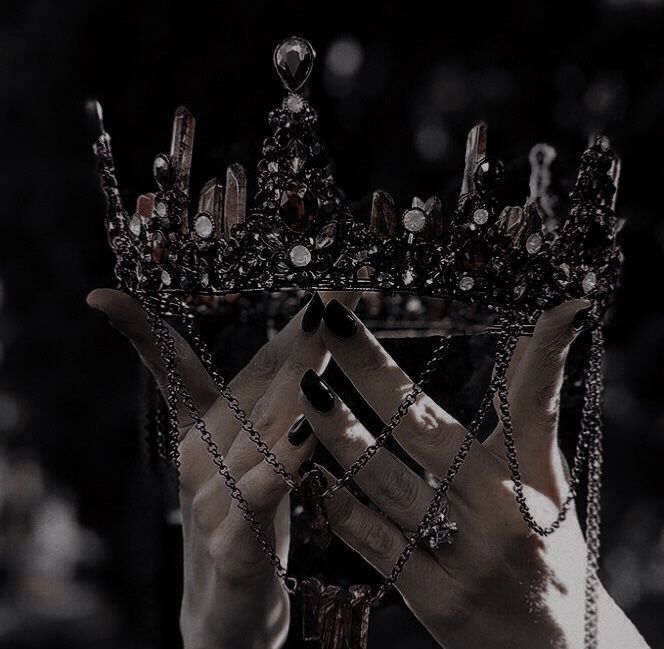 a black and white photo of a woman wearing a crown with chains around her hands