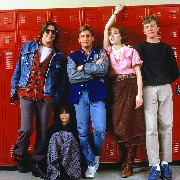 four people standing next to each other in front of lockers