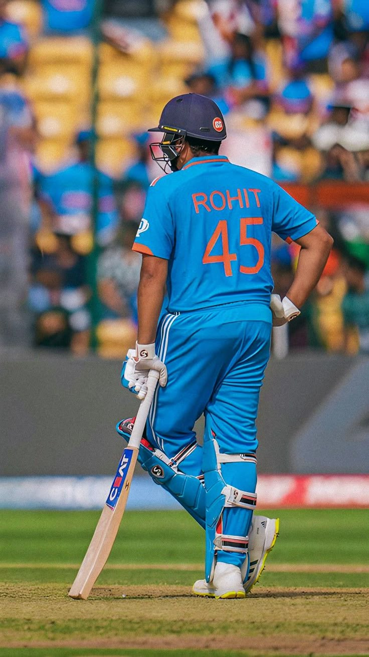 a man holding a cricket bat on top of a field in front of a crowd