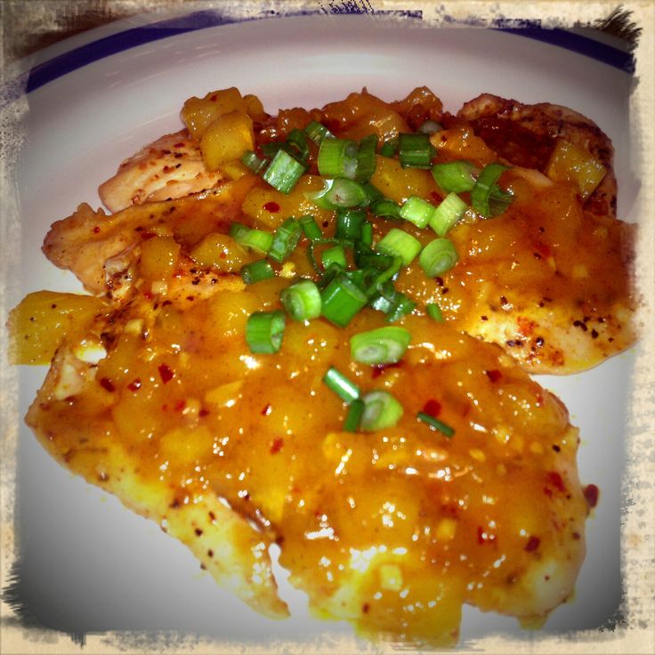 chicken with sauce and green onions on a white plate