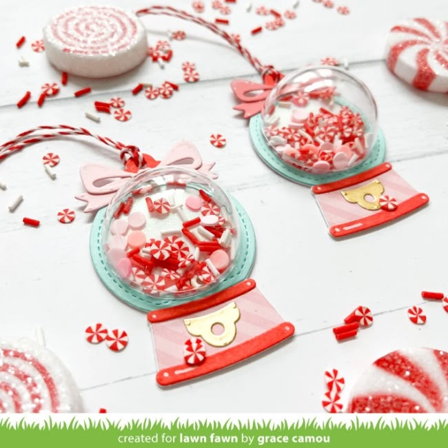 two glass ornaments with red and white confetti in them on top of a table