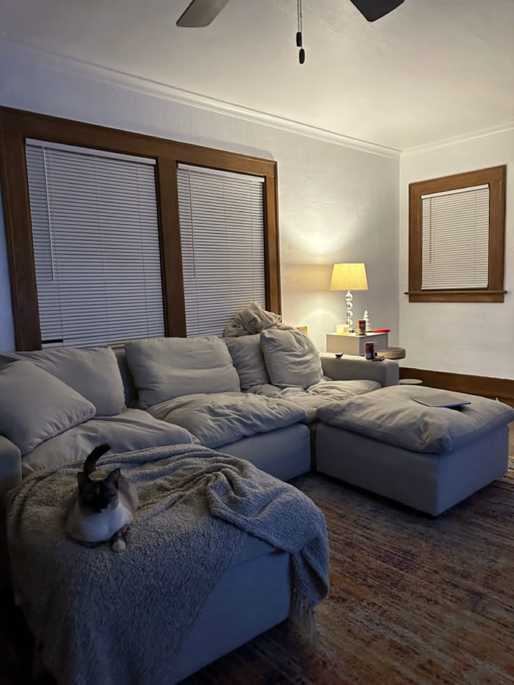 a living room with a large sectional couch and a cat sitting on the floor next to it