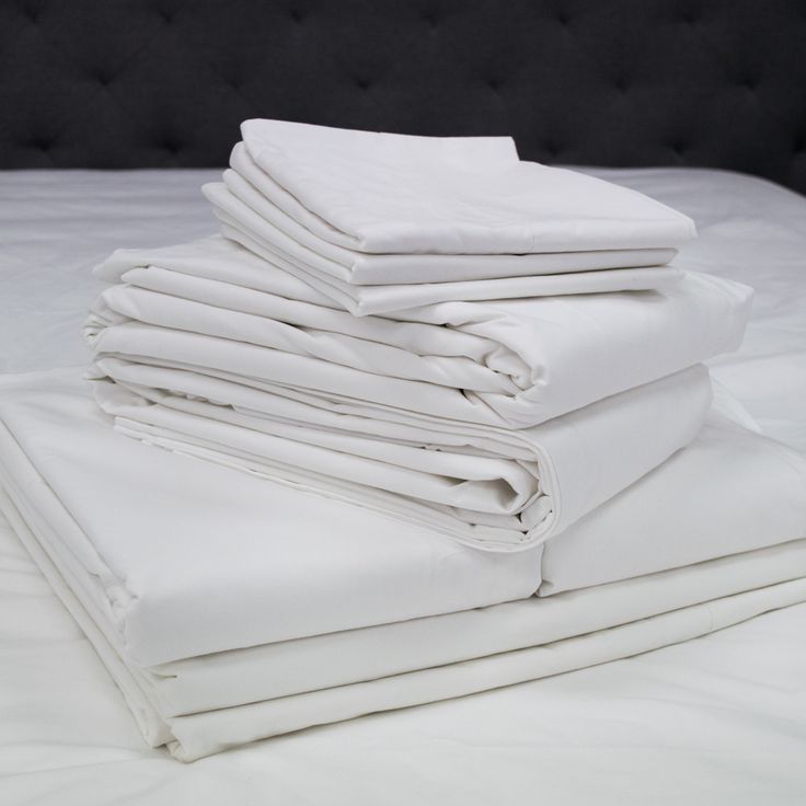 a stack of white sheets sitting on top of a bed