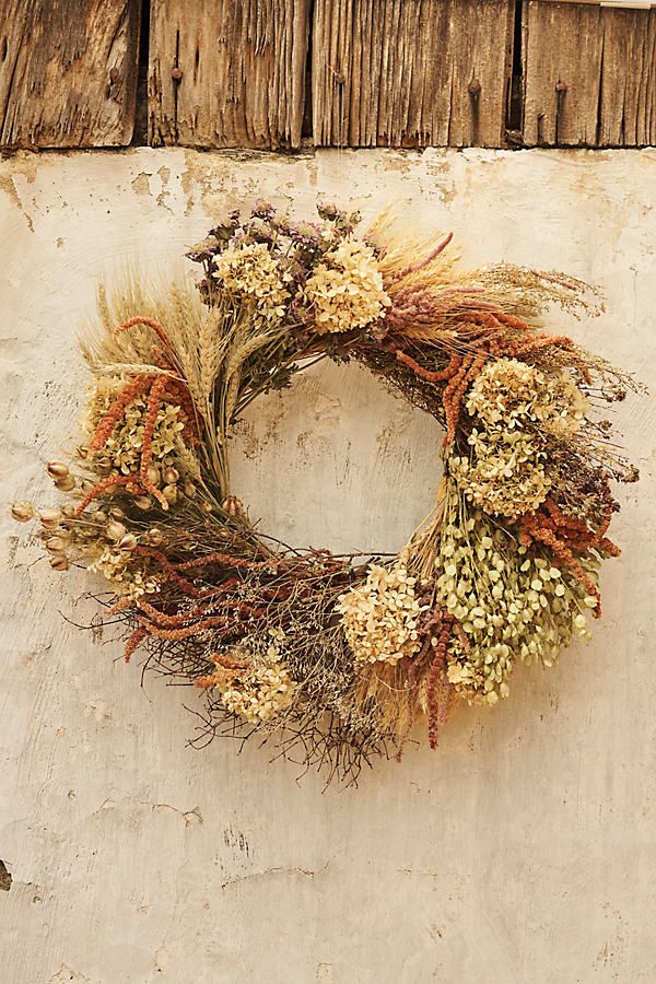 a dried wreath hanging on the side of a building