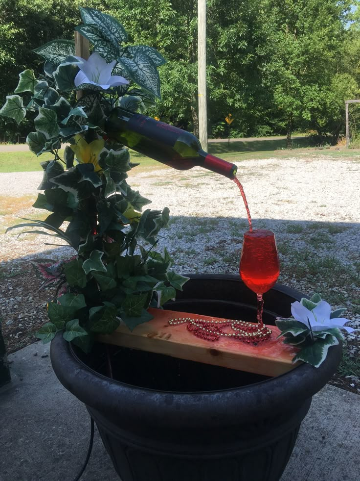 a wine glass being poured into a potted plant