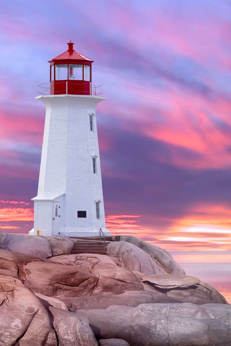 a lighthouse on top of a rock in the ocean at sunset with pink and purple clouds