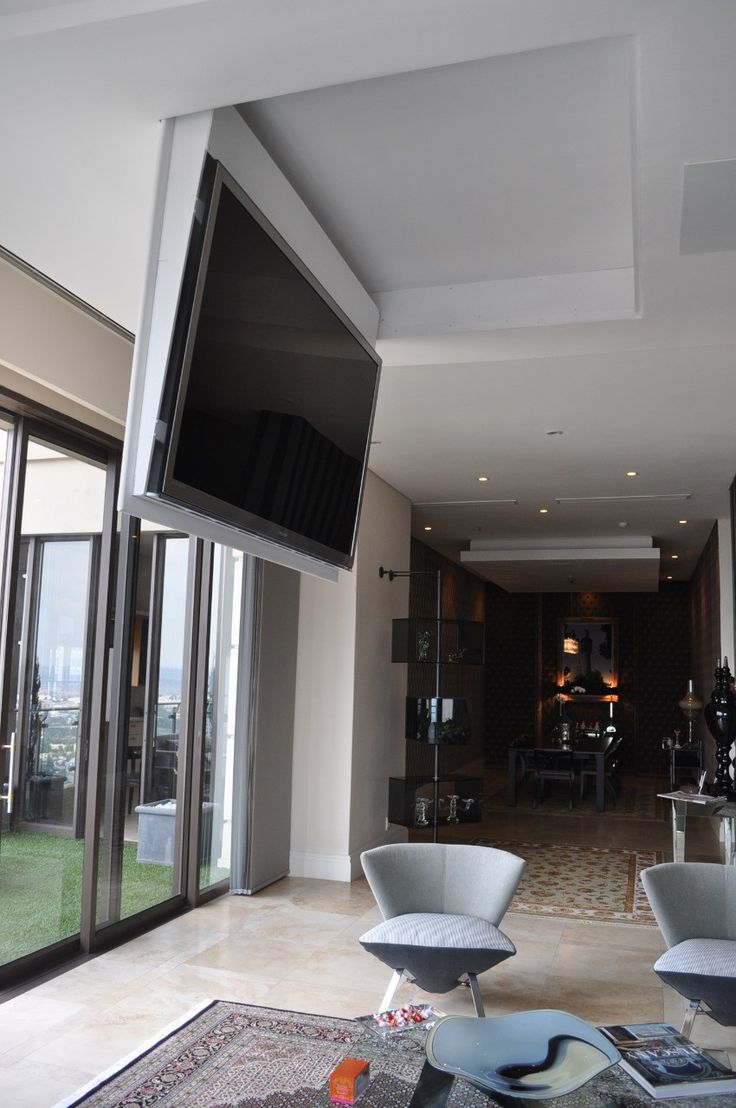 a living room with two chairs and a flat screen tv mounted to the wall above them