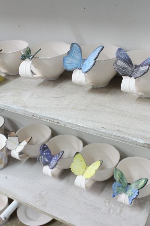 there are many cups and saucers that have butterflies on the top one is white