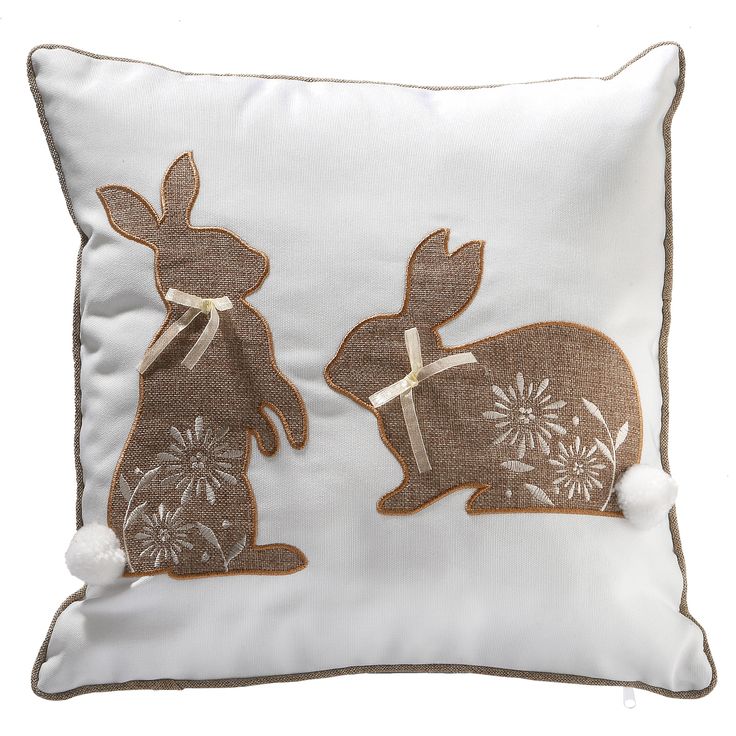 a white pillow with two brown rabbits on the front and one is holding a bow