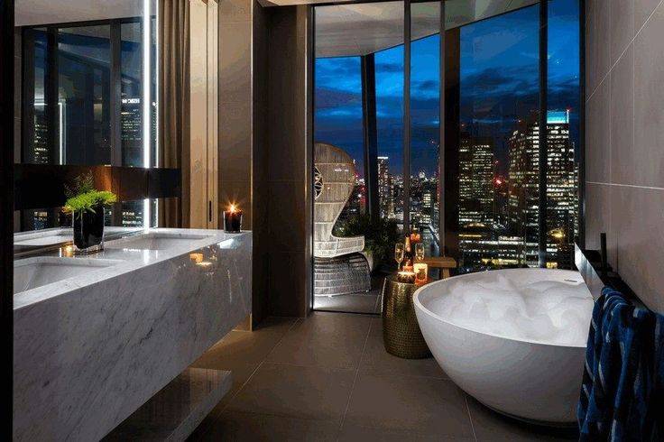 a large bathroom with two sinks and a bathtub in front of a city view