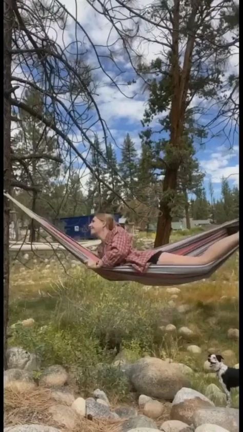 a man laying in a hammock with his dog watching from the other side