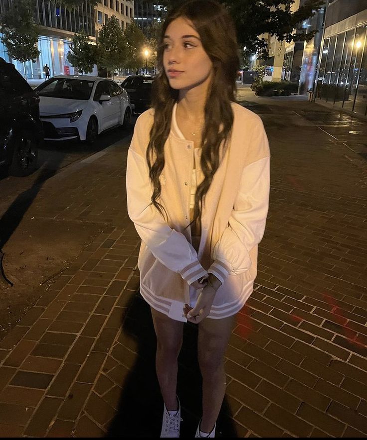 a woman with long hair standing on the sidewalk