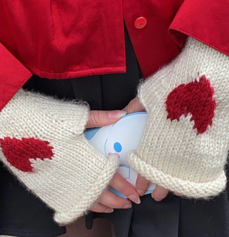 a person wearing red and white knitted mitts holding a small object