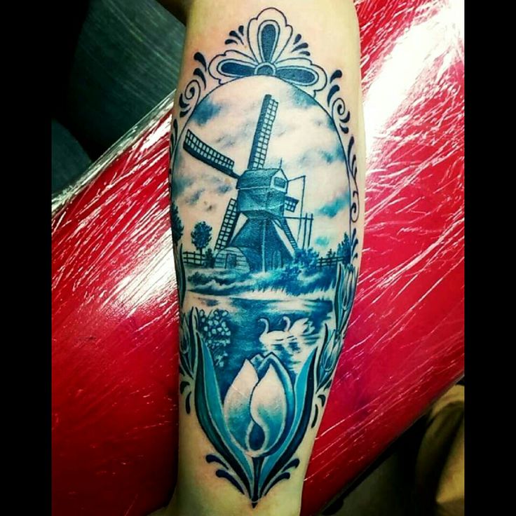 a blue and white tattoo with a windmill in the middle on someone's leg