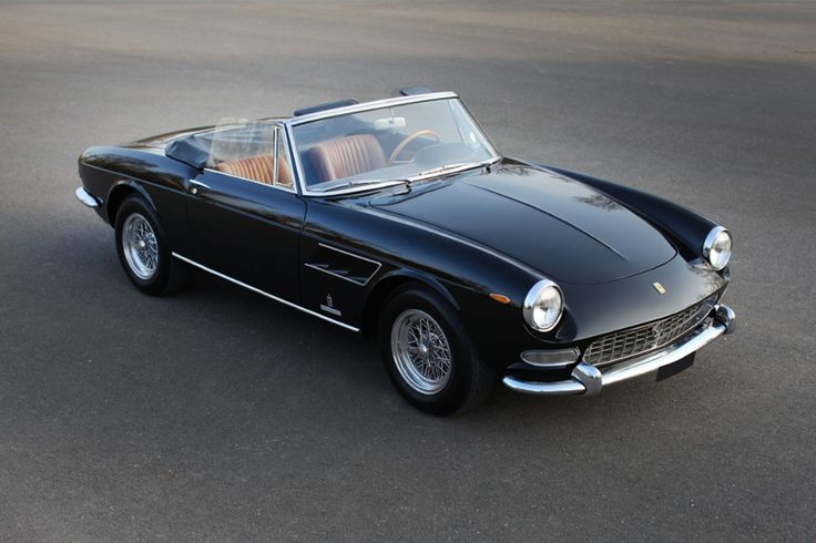 an old black sports car parked in a parking lot