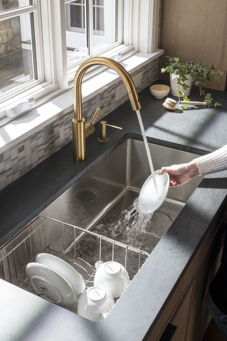 a person washing dishes in a kitchen sink