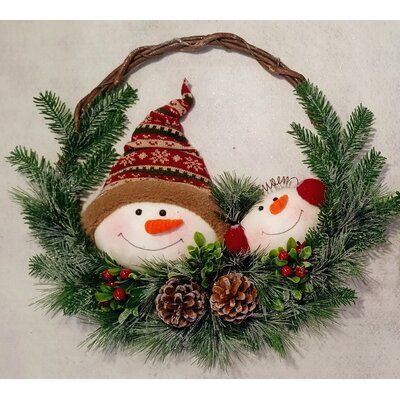 two snowmen are sitting in a wreath with pine cones and evergreen leaves on it