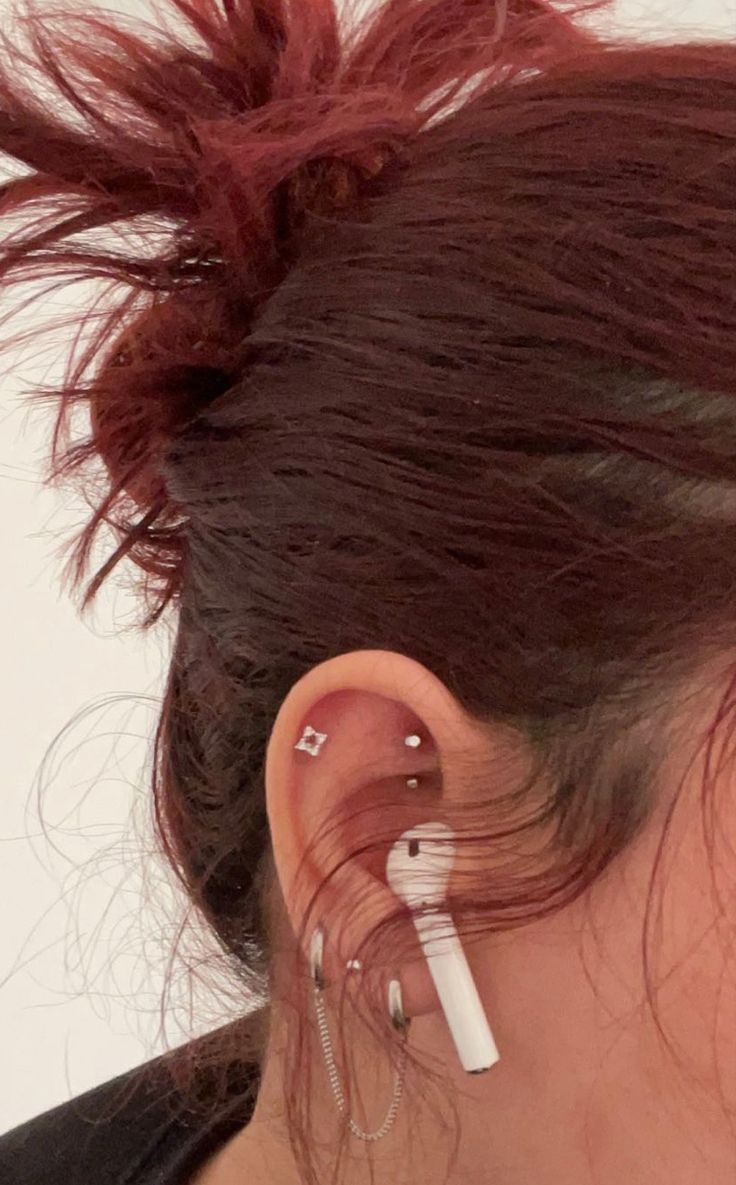 a woman with red hair wearing ear piercings and an earring on her left side