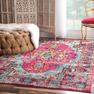 a colorful area rug with an ornate design on the floor and a red chair in front