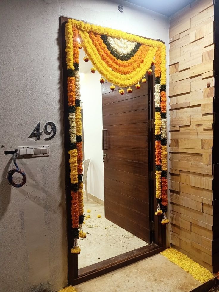 an entrance decorated with flowers and garlands in front of a wooden door to a bathroom