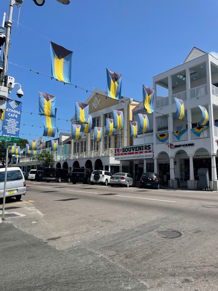 an intersection with cars parked on both sides and flags flying in the air above them