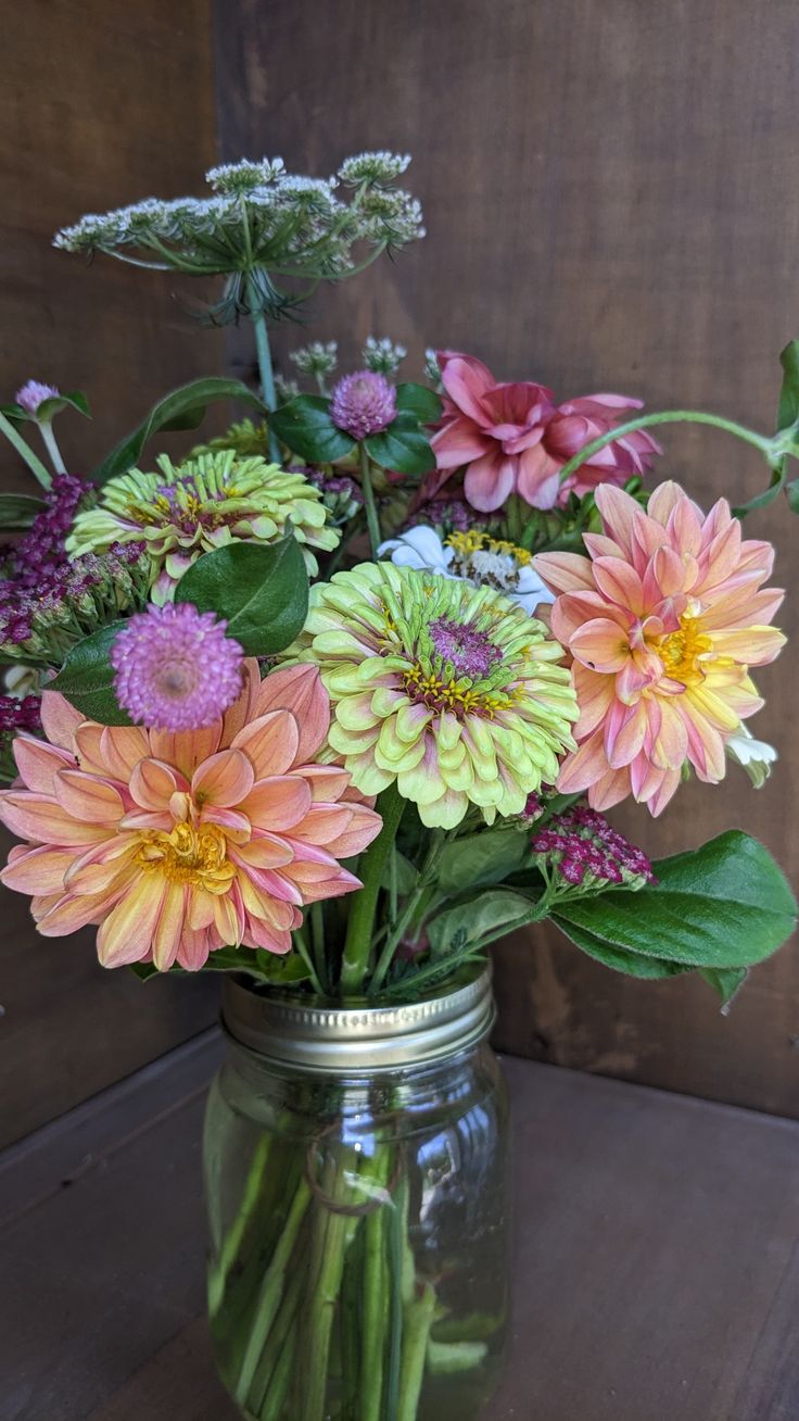 a mason jar filled with lots of colorful flowers